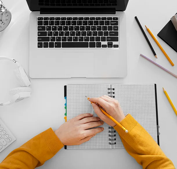 A person planning work beside a laptop